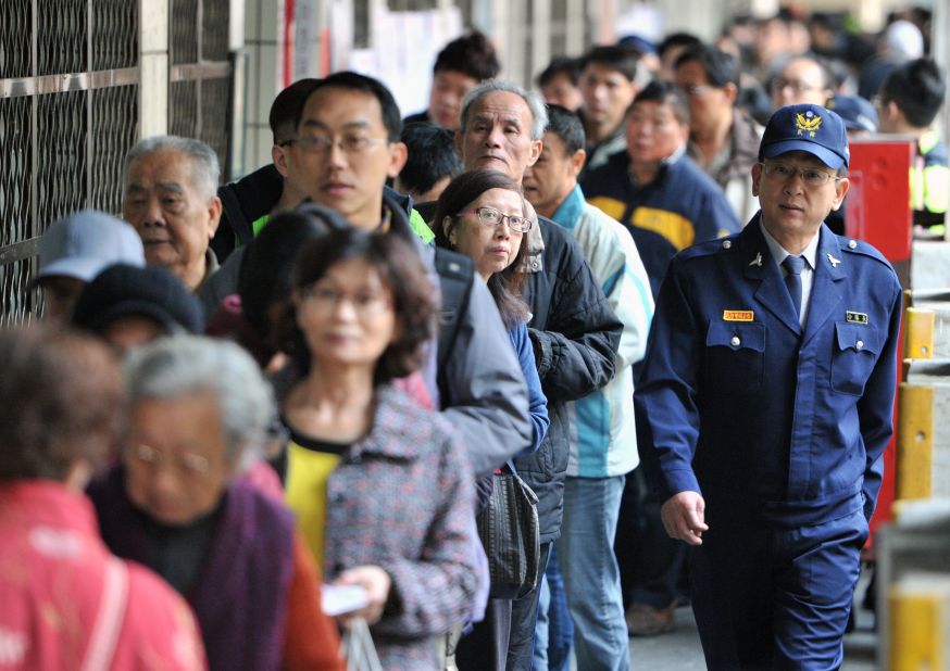 A police officer patrols a polling station as local residents line up at the Xindian district in Taipei.