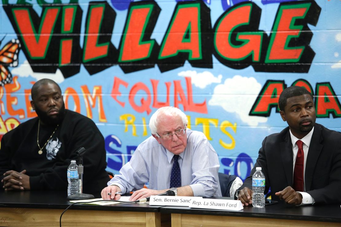 Rapper Killer Mike, left, listens as Bernie Sanders speaks during a roundtable meeting with local activist and community members December 23, 2015, in Chicago.
