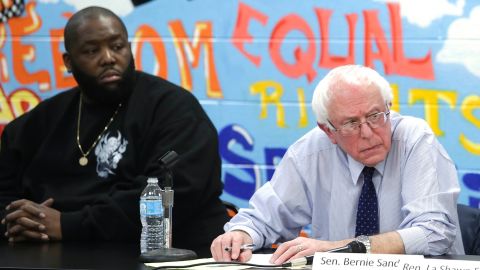 Rapper Killer Mike, left, listens as Bernie Sanders speaks during a roundtable meeting with local activist and community members December 23, 2015, in Chicago.