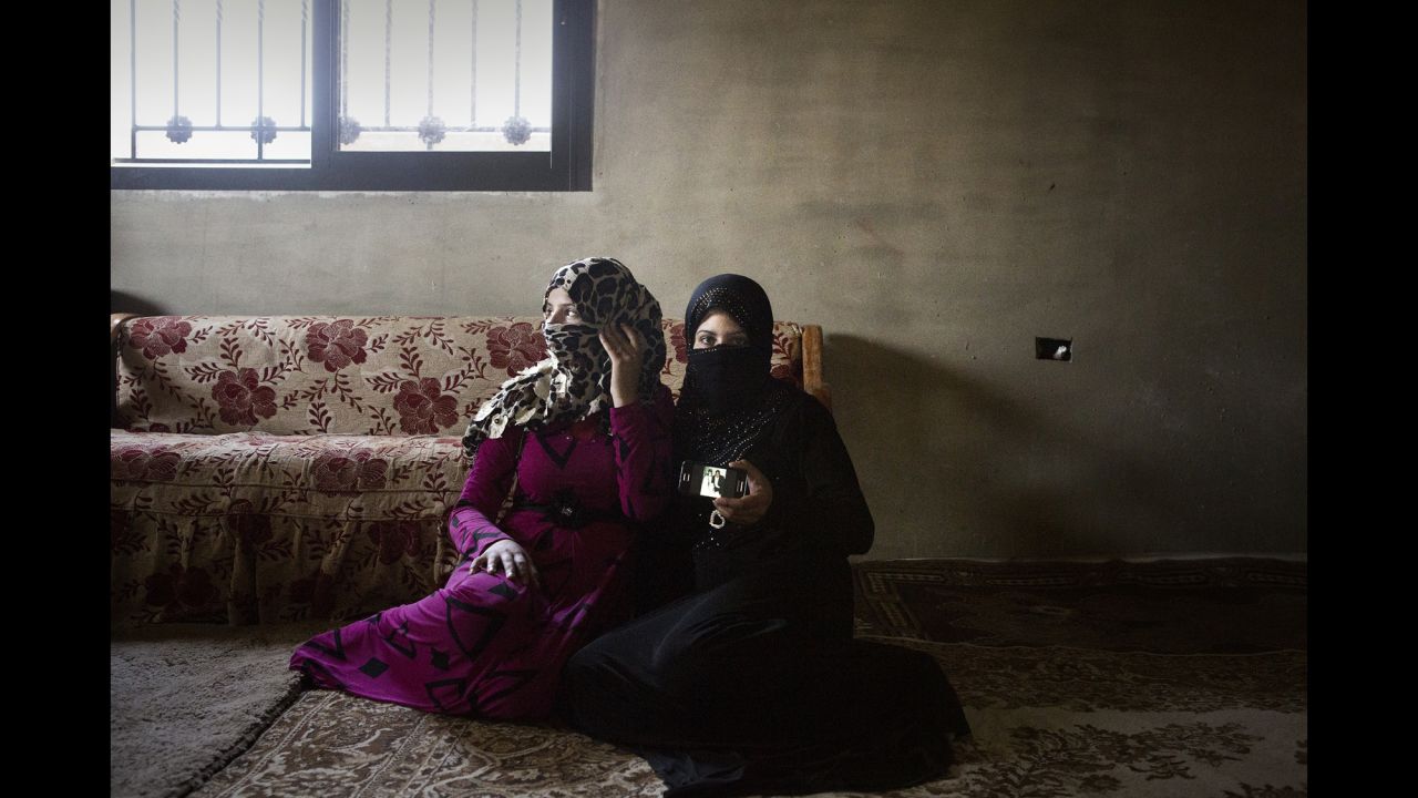 Houda, 14, and Nour, 13, show their wedding photos. They are sisters. Nour has already had a miscarriage.