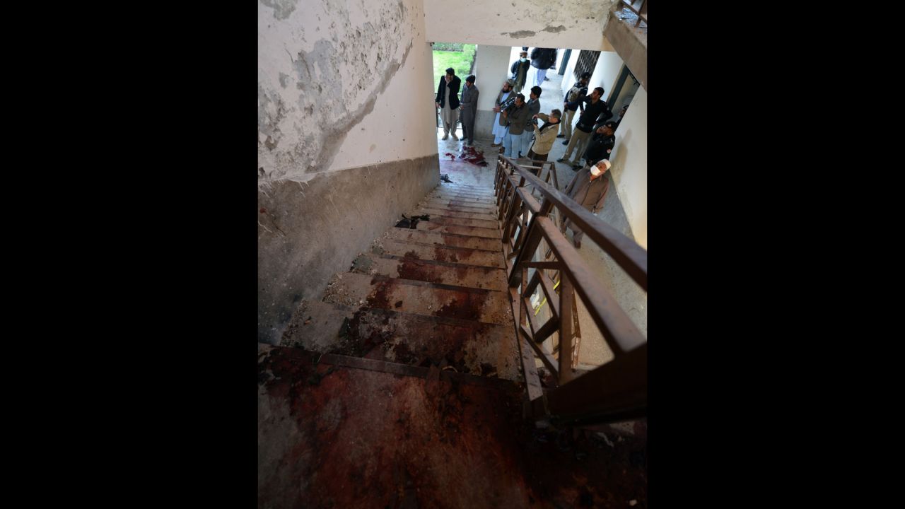 Policemen stand at the bottom of stairs splattered with blood where militants were killed.