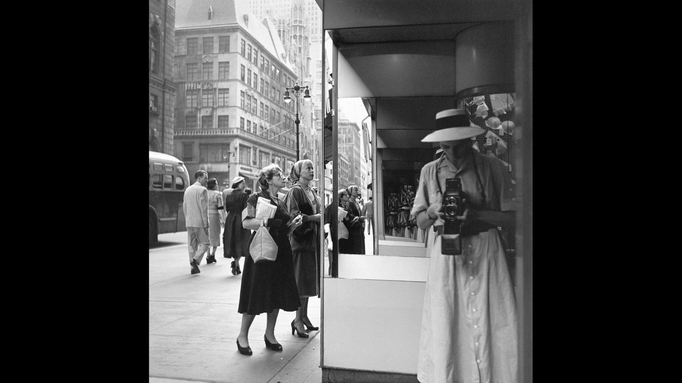 In this self-portrait from the 1950s, Maier photographs herself in the corner of a street, likely unnoticed by those around her. In fact many, if not all, of Maier's self-portraits produce this conflicting and unsettling notion of feeling invisible or alone even when surrounded by people.