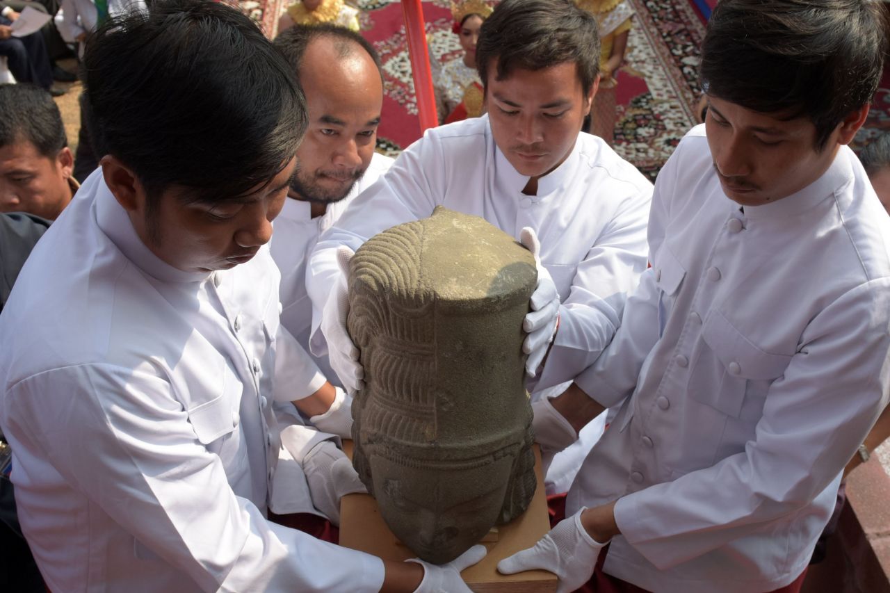 Museum employees carry the head of the Harihara statue during a ceremony connecting the head to the body.