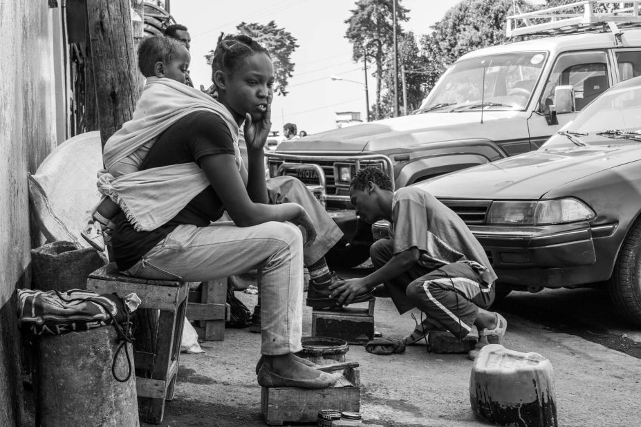 Meseret contemplates as she waits for a customer.  <br /> "Being a shoeshine girl is not common here. People prefer to get their shoes shined by men. Sometimes the shoeshine boys tell me to go away and find another place to work because they feel like I am taking away their income. Mostly I just ignore them but sometimes I do have to leave.  But not all of them are mean to me. Some actually care. They hold my daughter for me while I work."
