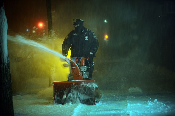 A New York City police officer uses a snow blower to clean the sidewalks on January 23.
