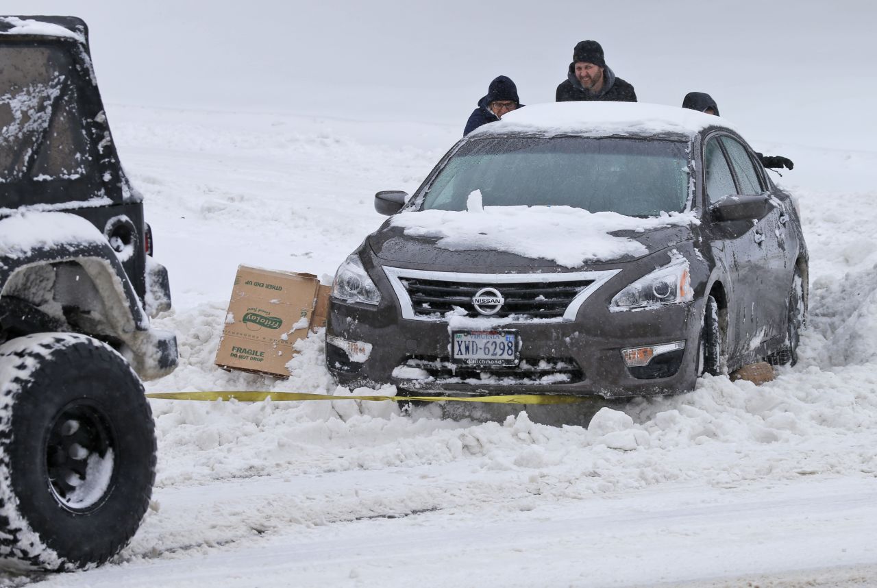 People help push a car out of the snow as another motorist tows it in Richmond on January 23.