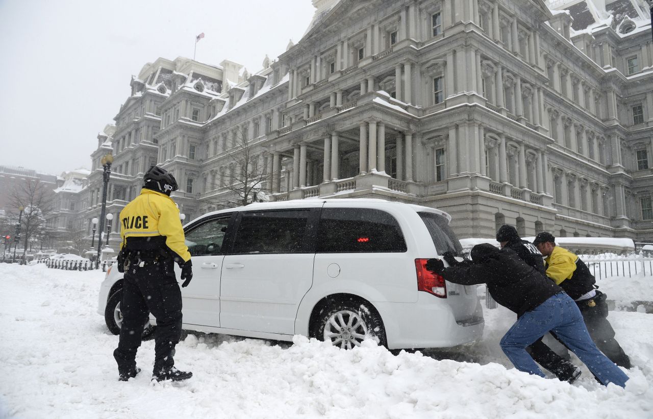Secret Service officers push a police car stuck in front of the Eisenhower Executive Office Building in Washington on January 23.
