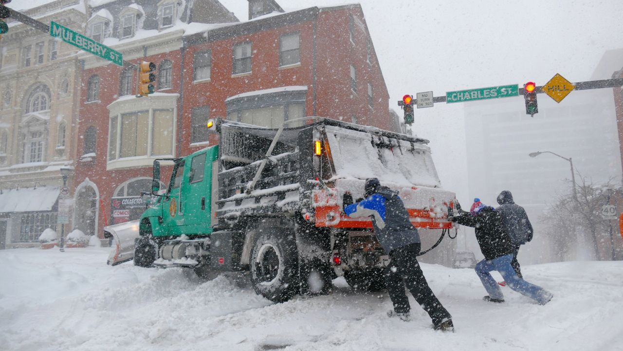Chris Holder, left, and Chris Hauger try to push a loaded six-wheel salt truck in Baltimore on January 23.