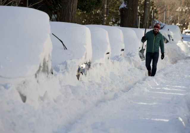 A man walks with a shovel past a line of snowed-in cars in Washington on January 24. 