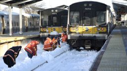Workers clear train tracks of snow at the Port Washington station on the Long Island Railroad in Port Washington, New York, on Monday, January 25.