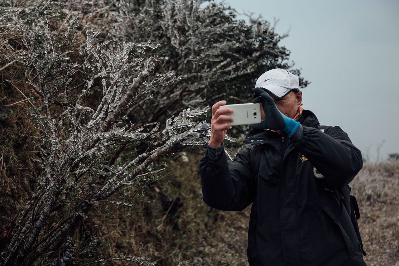 A hiker takes a photo of a frozen plant in sub-zero temperatures atop Hong Kong's highest peak on Sunday, January 24. Temperatures plunged to the lowest point in 59 years and frost dusted the mountaintops of a city accustomed to a more subtropical climate.  