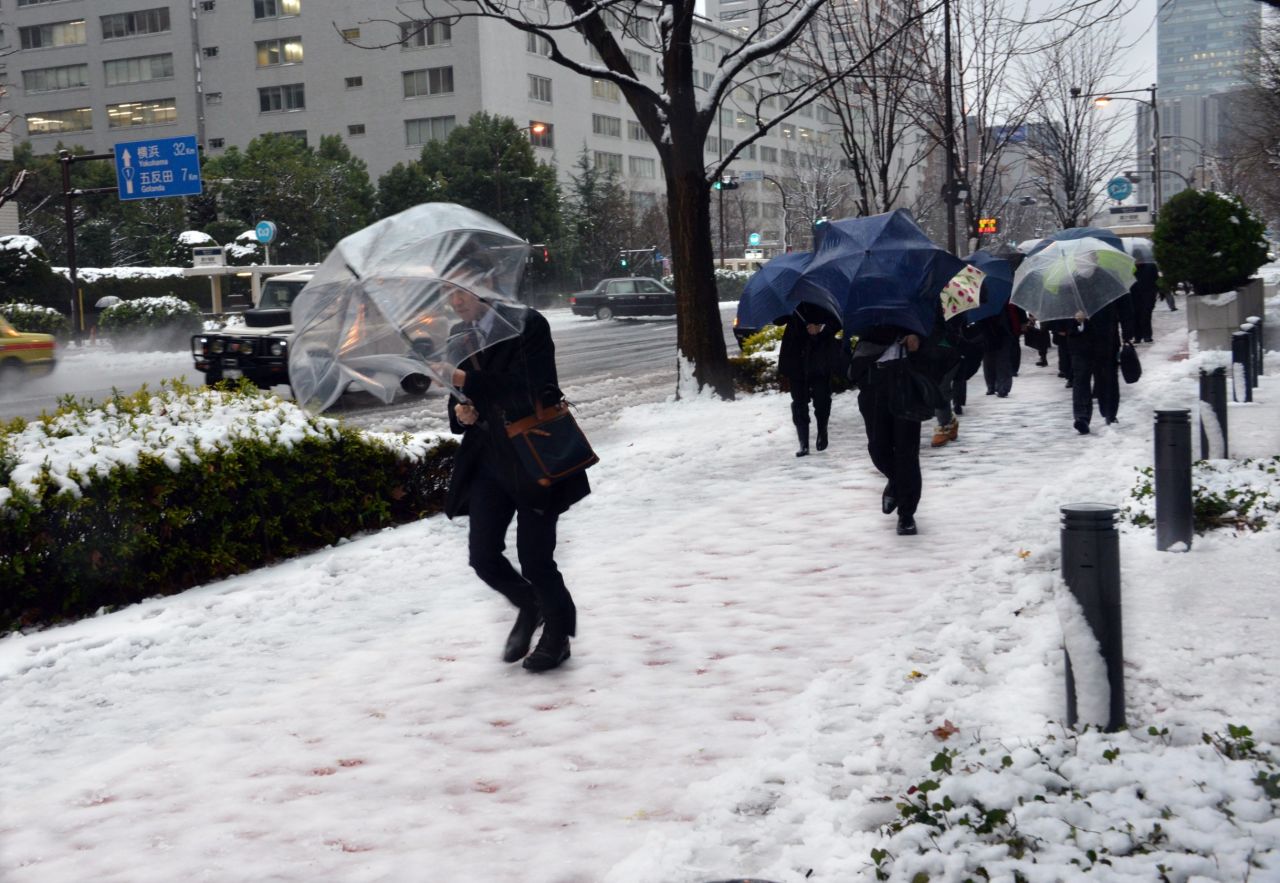 Commuters walk on a snow covered road in Tokyo on January 18 where heavy snow blanketed the metropolitan area and transportation systems were paralyzed. Many cities throughout western and northern Japan have seen record snow falls, while the usually-warm Okinawa island saw snowfall for the first time ever since record-keeping began in 1966.