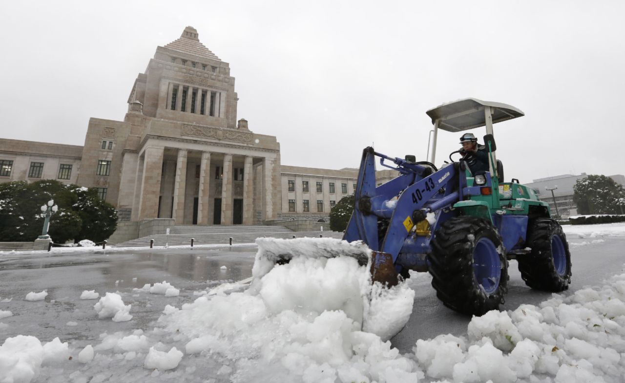 A man removes snow from the forecourt of the Diet building in Tokyo on January 18. Japanese transportation authorities said that over 60 flights were canceled due to heavy snow.