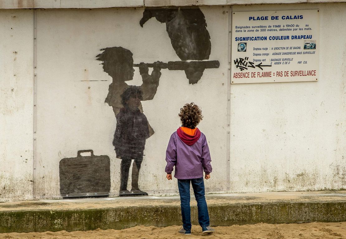 A child looks at a Banksy mural representing migrant children, in Calais in December 2015.