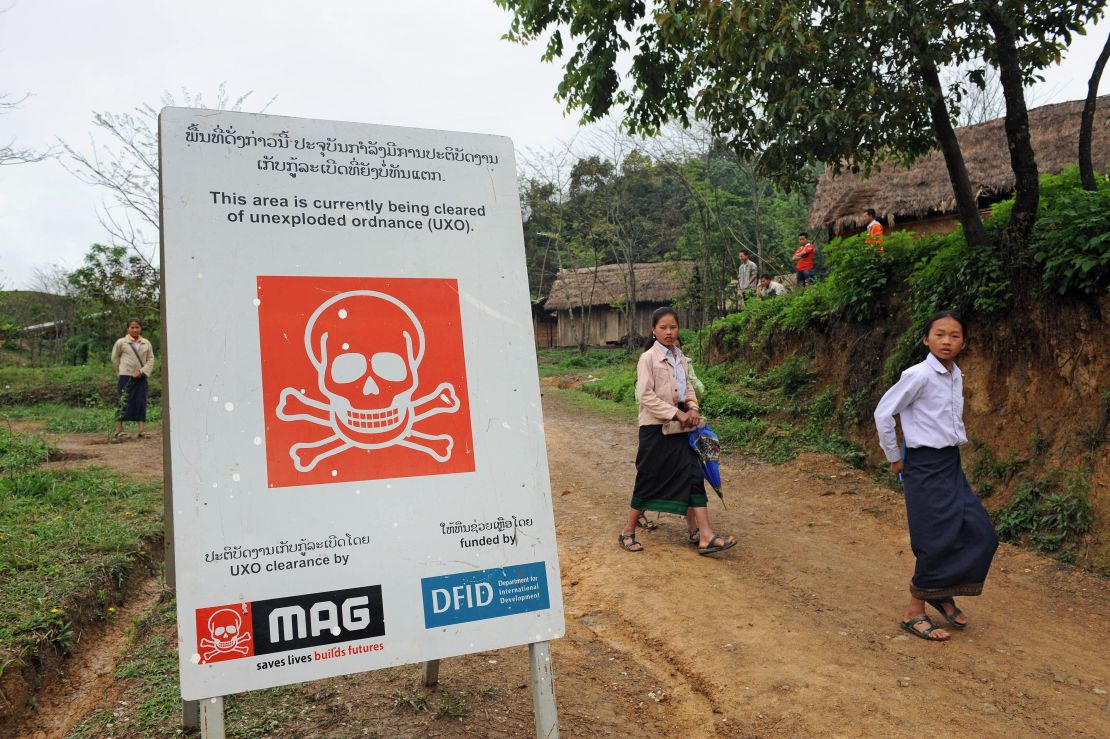 Students walk past a poster warning of a mine clearance operation by clearance team at a secondary school in the northern Laotian province of Xiangkhoang. During the Vietnam War, Laos became the world's most heavily bombed country per head of population.