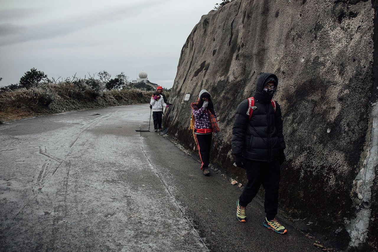 Hikers walk on icy road in sub-zero temperature on Tai Mo Shan, Hong Kong's highest peak on January 24. Many looking for sights of snow and frost in the subtropic city were trapped on the city's highest mountains as a result of iced-over roads and extreme cold.