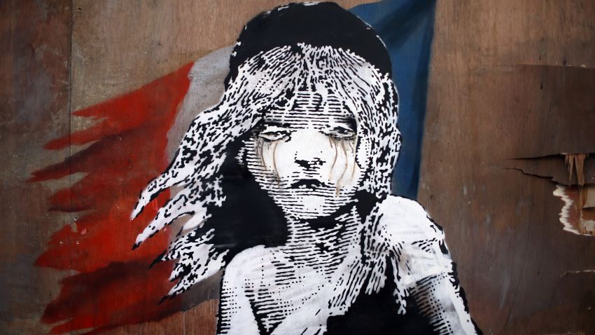 LONDON, ENGLAND - JANUARY 25:  A Banksy artwork is created opposite the French embassy on January 25, 2016 in London, England. The graffiti, which depicts a young girl from the musical Les Miserables with tears in her eyes as CS gas moves towards her, criticises the use of teargas in the 'Jungle' migrant camp in Calais.  (Photo by Carl Court/Getty Images)