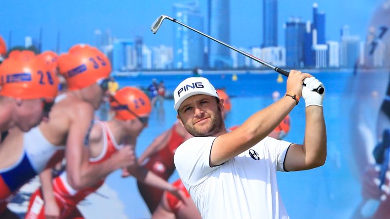 A triathlon advertisement is the backdrop for golfer Andy Sullivan as he plays a shot at the Abu Dhabi Championship on Friday, January 22. 