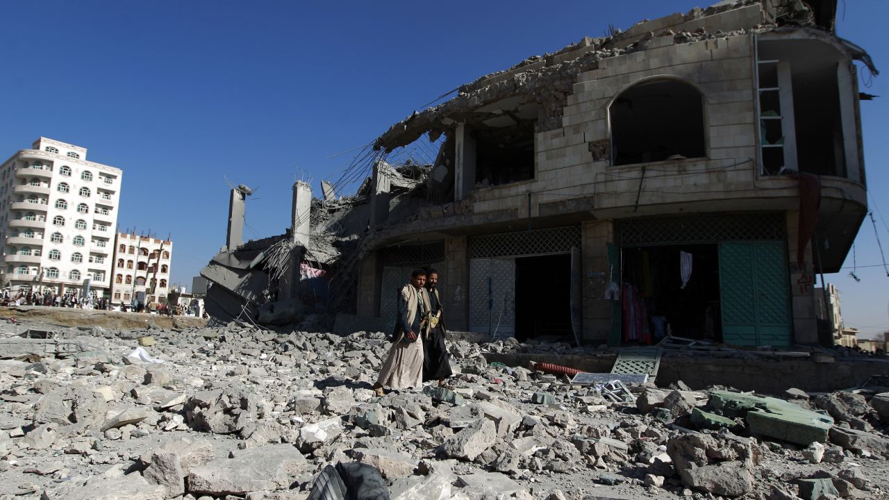 Yemenis walk past the site of a Saudi-led airstrike in Sanaa on January 25, 2016.