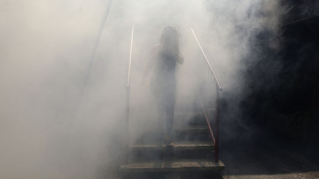 A woman walks through a haze of pesticide in  El Salvador.