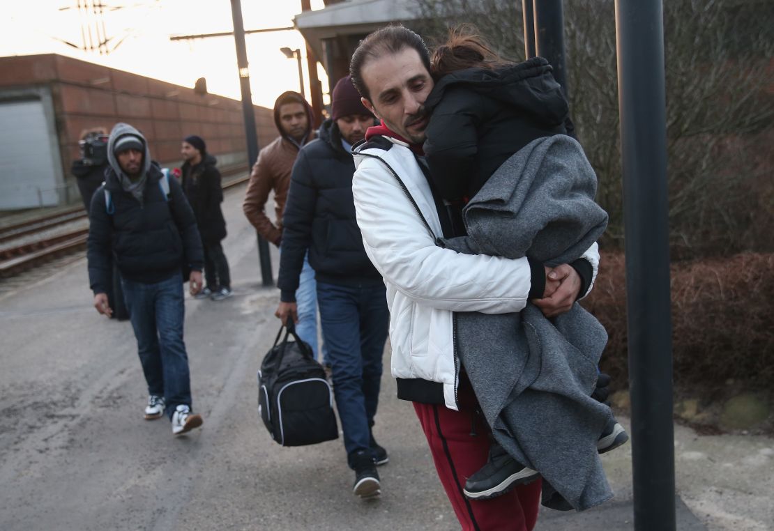 Asylum-seekers, many of them Syrian, walk to police vans on January 6, 2016 in Padborg, Denmark. 