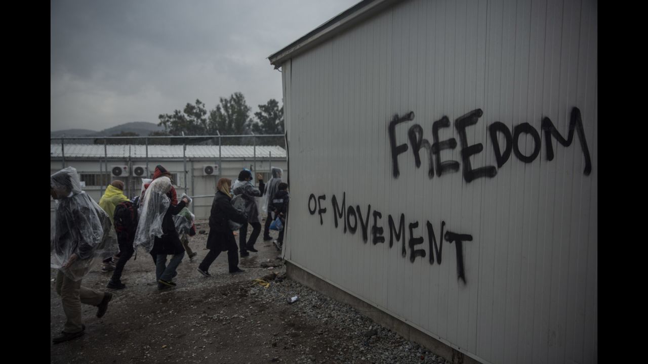 Refugees walk on January 10 in front of graffiti outside a registering center in the village of Moria on Lesbos.