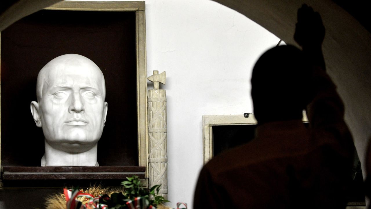 A far-right miliant makes a Fascist salute at Mussolini's tomb at a rally in 2012. 