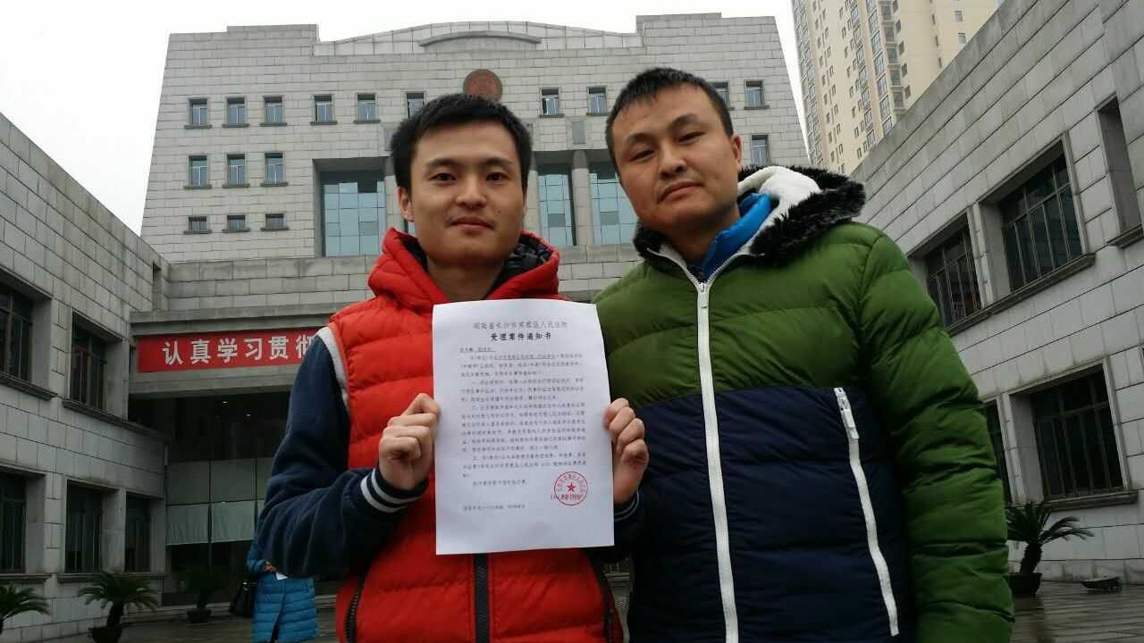 Sun Wenlin (left) and his partner Hu Mingliang stand in front of the Changsha Furong District People's Court on January 5, 2016, the day the court accepted their suit against the marriage registry.