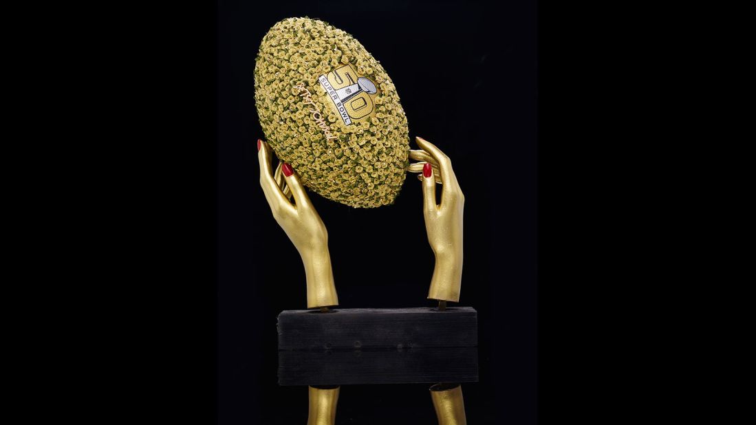 The National Football League has teamed up with 50 designers from the Council of Fashion Designers of America on a series of wildly embellished footballs. This <strong>Betsey Johnson</strong> piece features gold rosettes. Take a look at the other wild designs...