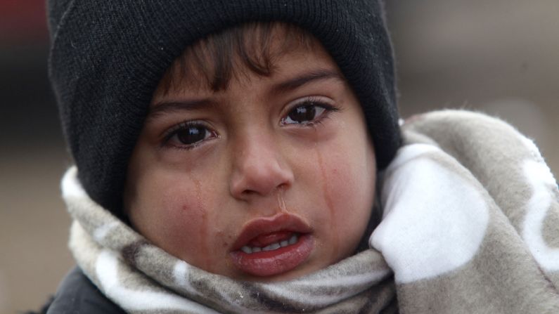 A young boy cries near the Miratovac refugee camp after arriving from Macedonia on a very cold winter morning.