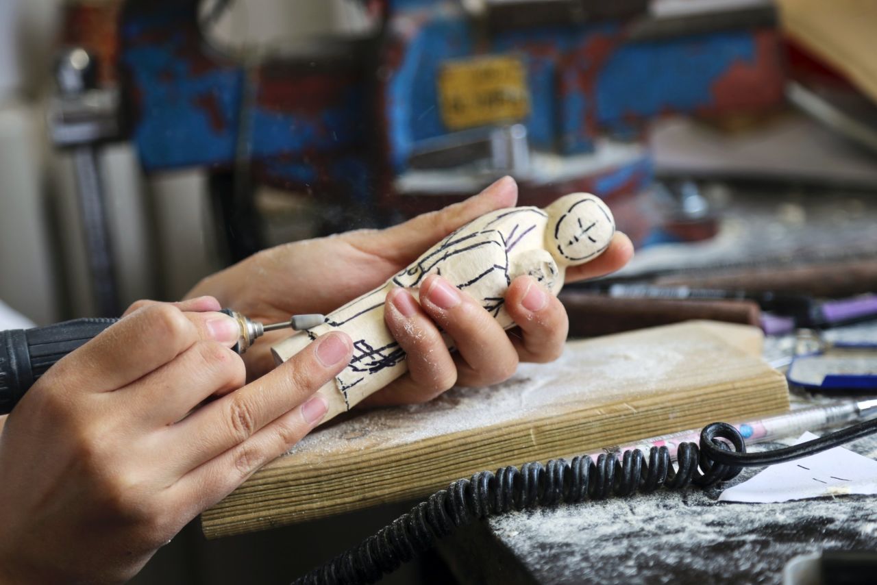 One of Li Chunke's apprentice ivory carvers practices her skills on a wood statuette.