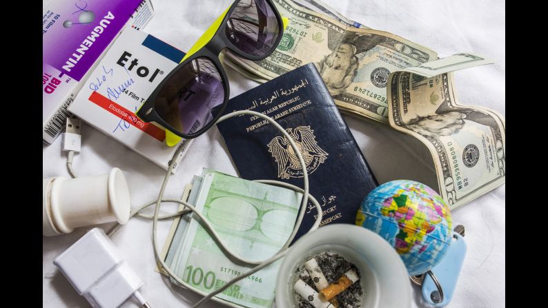 A close-up of Somar's Syrian passport, along with money and a few other objects.