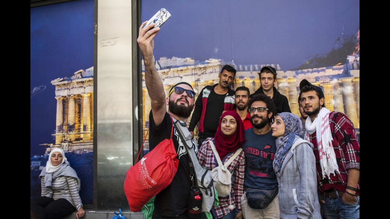 Somar and his sisters take a selfie with friends in front of an Acropolis photo in Athens, Greece.