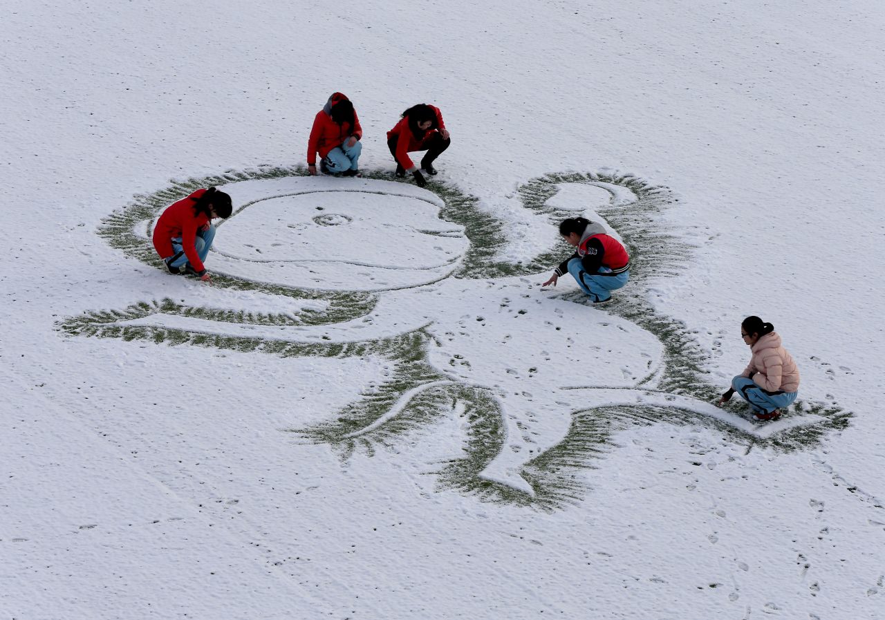 A teacher and students draw a monkey on the snow-covered ground in China's Jiangsu Province on Thursday, January 21. 