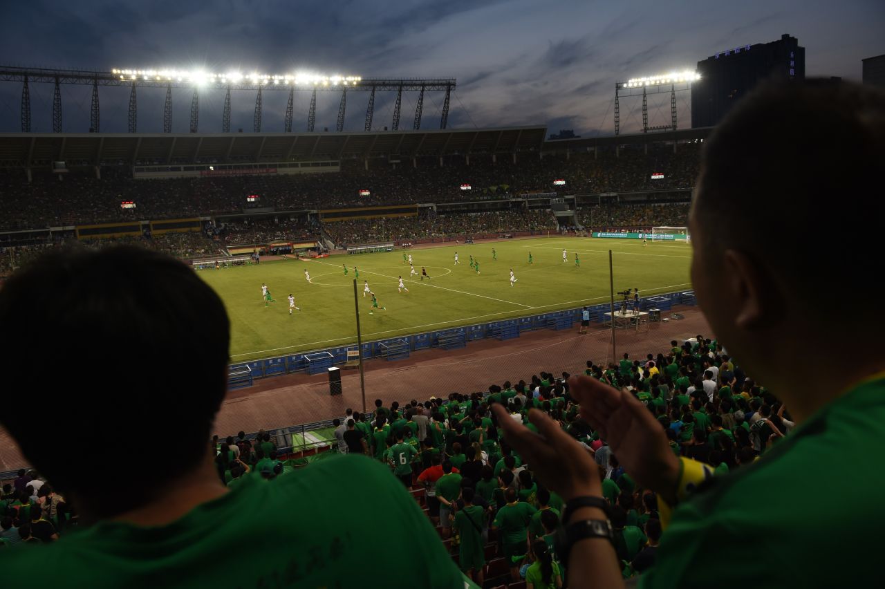 This photo taken on June 20, 2015 shows fans (foreground) wearing the colors of the Beijing Guoan team as they watch the team's Chinese Super League  match against Tianjin Teda in Beijing. 
