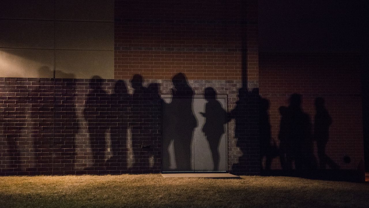 The shadows of lined-up caucusgoers are seen outside a school in West Des Moines.