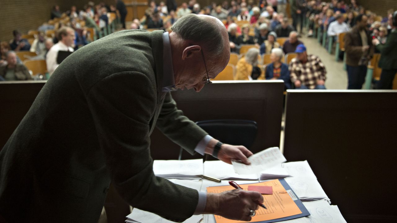 Paper ballots are counted at a middle-school auditorium in Des Moines.