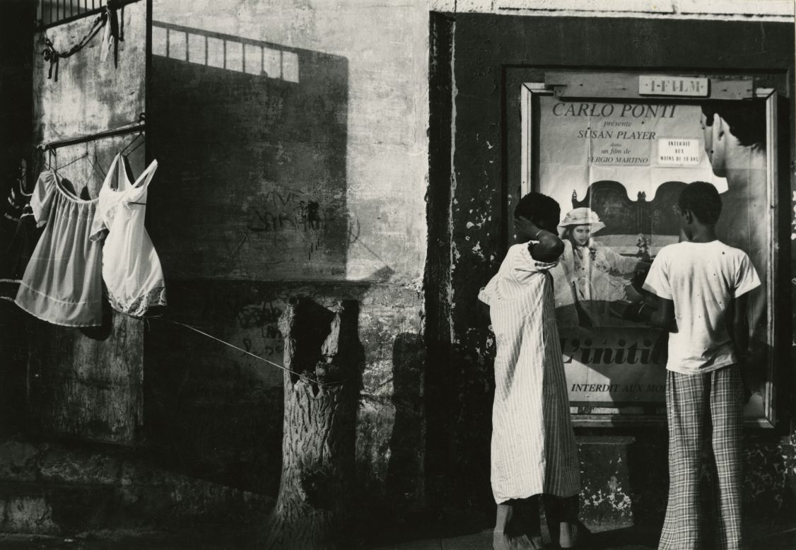Draper occasionally left New York to photograph the world. This photo, taken in 1978 in Dakar, Senegal, shows a man and a woman next to a poster for an Italian B movie.