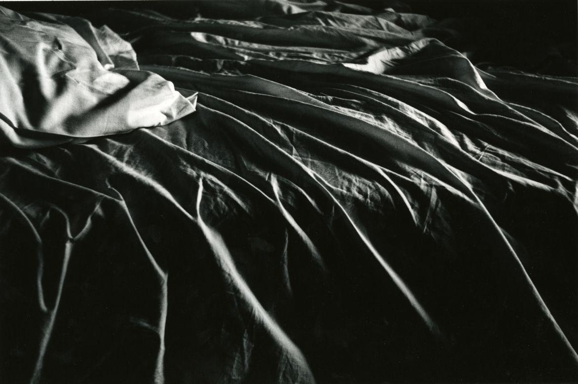 This 1958 image shows the interplay of light and shadow on the linens of an unmade bed.