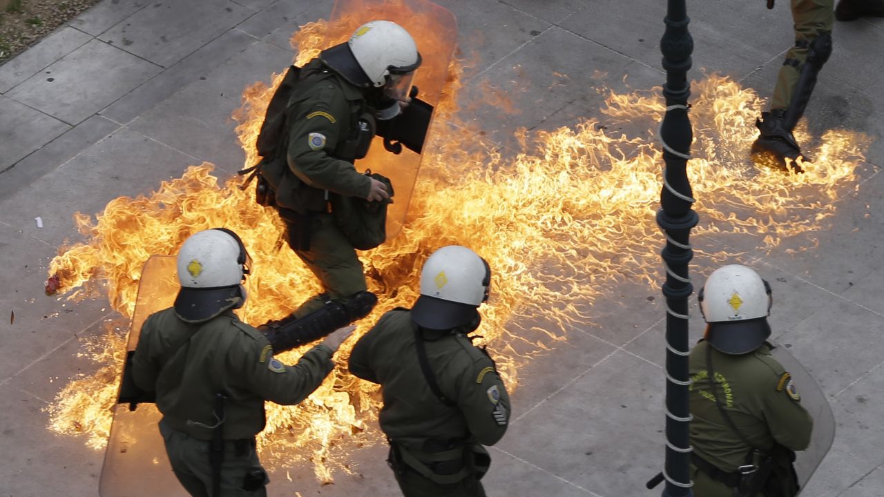 Riot police in Athens, Greece, try to avoid a Molotov cocktail thrown by protesters during a nationwide strike on Thursday, February 4. Clashes broke out as tens of thousands of people protested pension reforms that are part of the country's latest economic bailout.