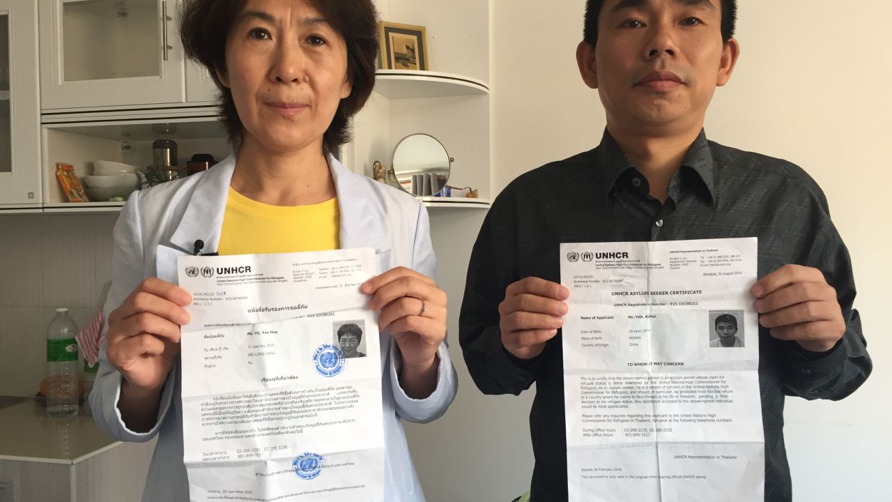 Chinese dissidents Yu Yanhua, left, and Yan Bojun pose with their U.N. asylum seeker documents from the UNHCR in Bangkok. They fled China together for safety in Thailand but now fear their government will come after them even outside of its borders.