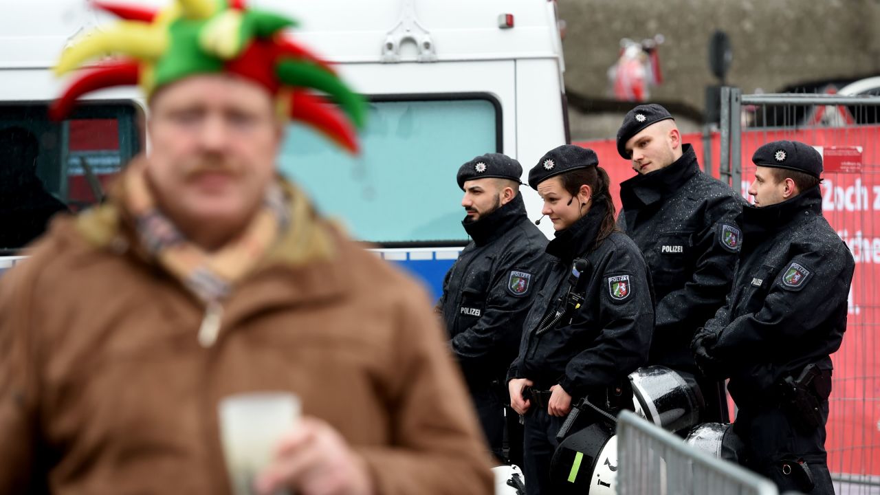 A jester stands in front of police officers near the central station in Cologne during the city's Carnival celebrations on February 4, 2016.