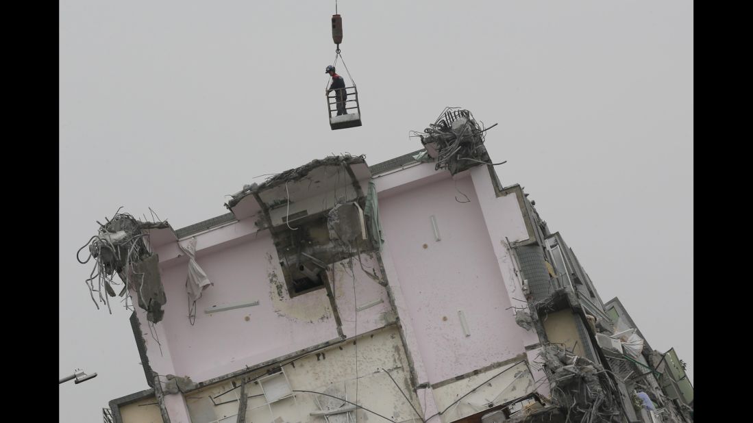 A rescue worker hangs from a crane while searching a collapsed building in Tainan.