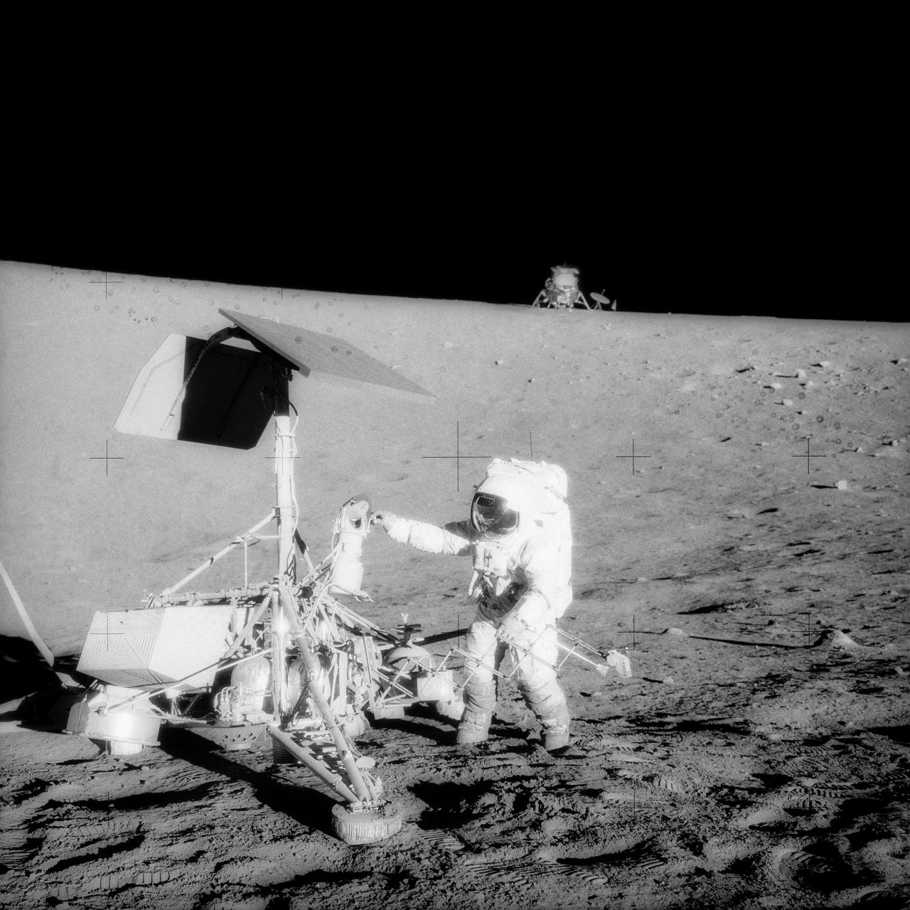 Conrad examines the Surveyor 3, a spacecraft that landed on the moon in 1967. The Apollo 12 crew touched down about 600 feet from the older spacecraft. They collected its television camera and several other pieces and brought them back to Earth.