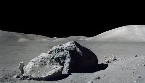Schmitt stands next to a huge lunar boulder during an Apollo 17 moonwalk. The lunar rover is in the background. Schmitt was the 12th man to set foot on the moon, but Cernan was the last to leave.