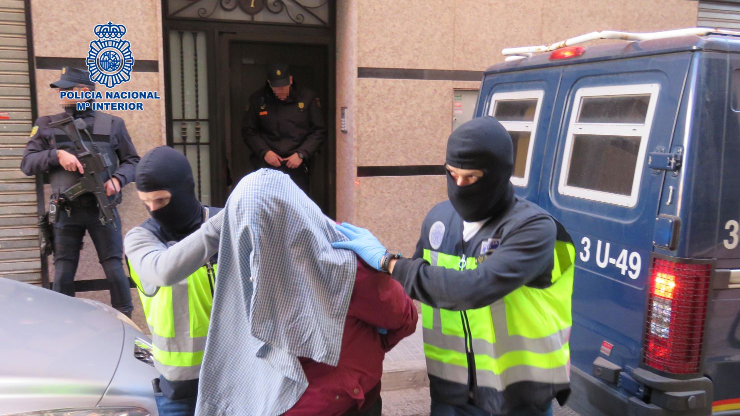 Spanish police wearing balaclavas escort one of the terror suspects arrested Sunday.