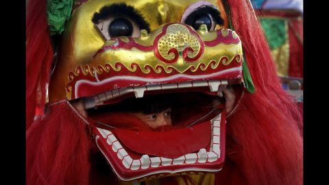 A performer looks out from the mouth of a lion head at Ditan Park in Beijing on February 8.