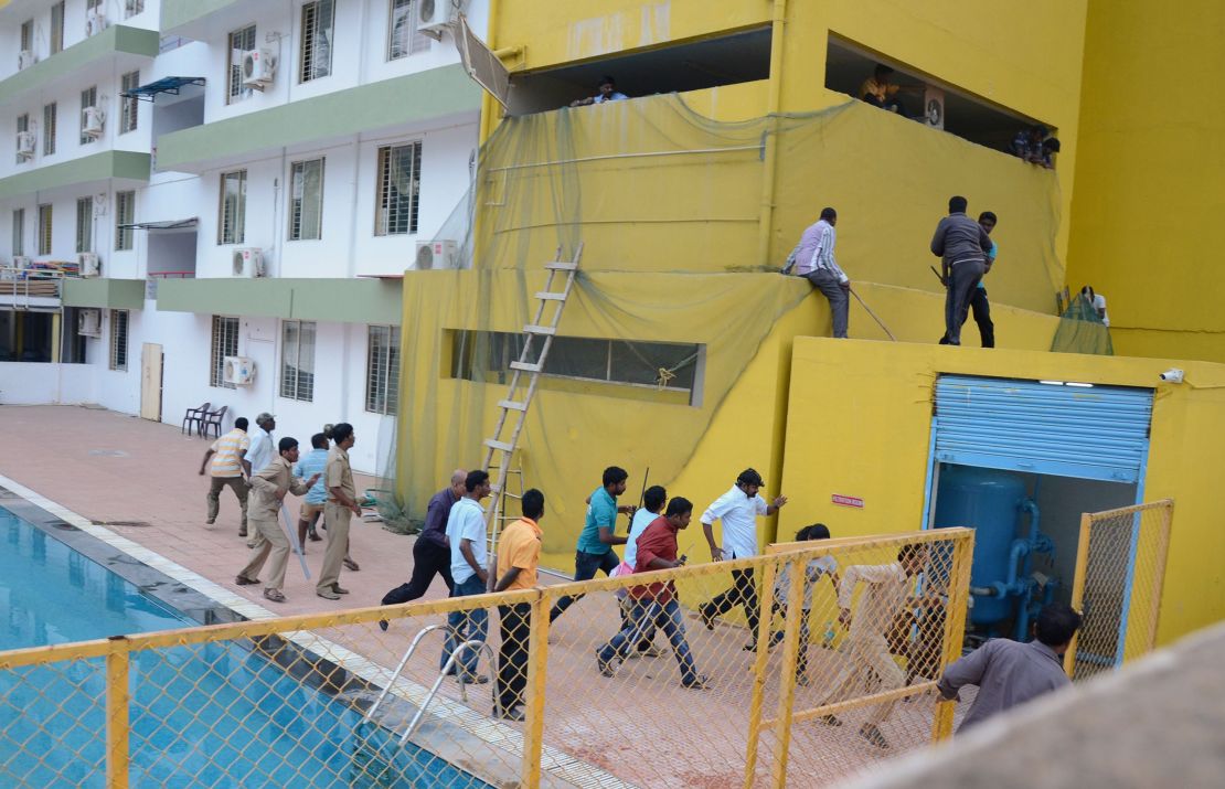 Panicked men run for safety as the leopard roams loose by the school pool Sunday in Bangalore.