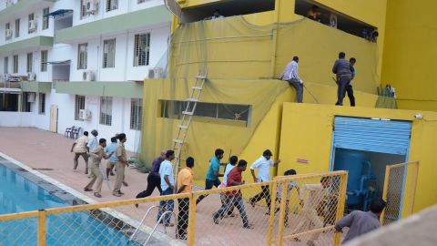 Panicked men run for safety as the leopard roams loose by the school pool Sunday in Bangalore.