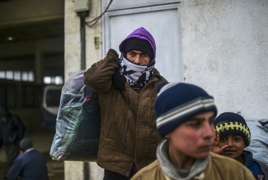 A refugee carries a heavy bag of items near the Turkish border gate on February 6.